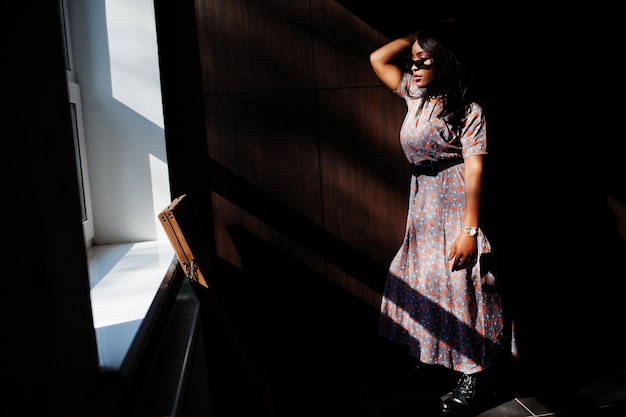 Jogo com sombras retrato de moda de mulher afro-americana em vestido longo e óculos internos