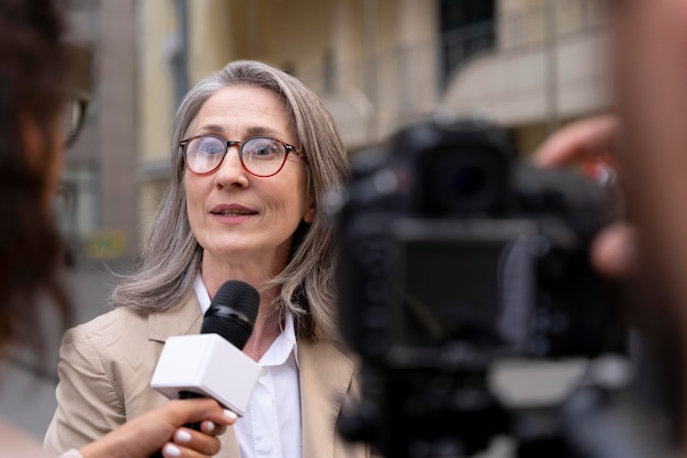 Foto grátis jornalista dando uma entrevista ao lado de seu cinegrafista