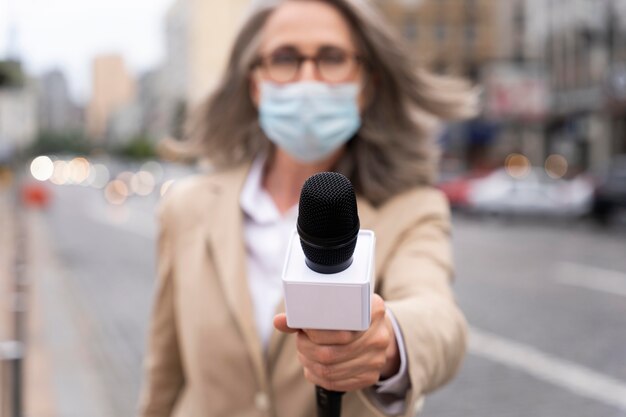 Jornalista de visão frontal segurando um microfone