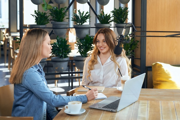 jornalista fazendo perguntas para a mulher blogueira no café