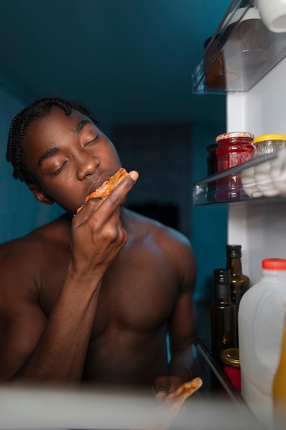 Jovem abrindo a geladeira em casa para um lanche no meio da noite