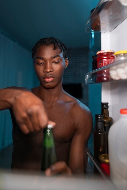 Jovem abrindo a geladeira em casa para um lanche no meio da noite