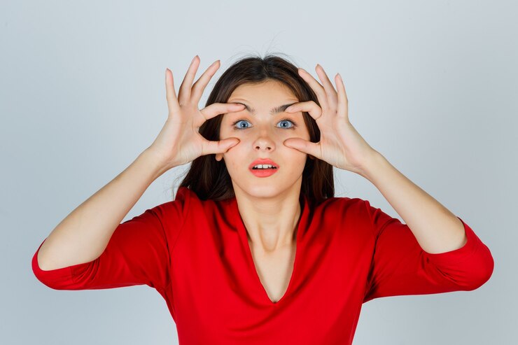 Foto grátis jovem abrindo os olhos para ver claramente de blusa vermelha e bonita