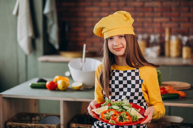 Jovem adolescente preparando salada para o café da manhã na cozinha