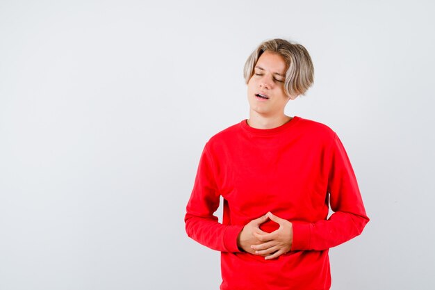 Jovem adolescente sofrendo de dor de estômago, vestindo uma camisola vermelha e parecendo incomodado, vista frontal.