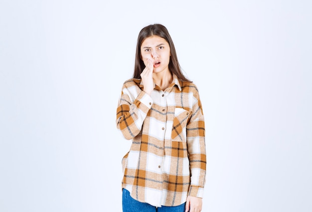 Jovem adorável mulher com roupas casuais, posando na parede branca.