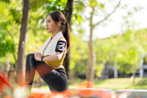 Jovem adulto alegre asiático Manhã atraente e forte se esticando antes de correr no parque Conceito esportivo Estilo de vida saudável Corredor de mulher jovem fitness se esticando antes de correr no parque