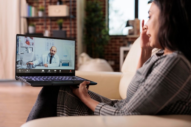 Jovem adulto chamando médico em telessaúde por videochamada, falando sobre tratamento de saúde em videoconferência e telemedicina. Reunião em teleconferência remota com médico, consulta online.