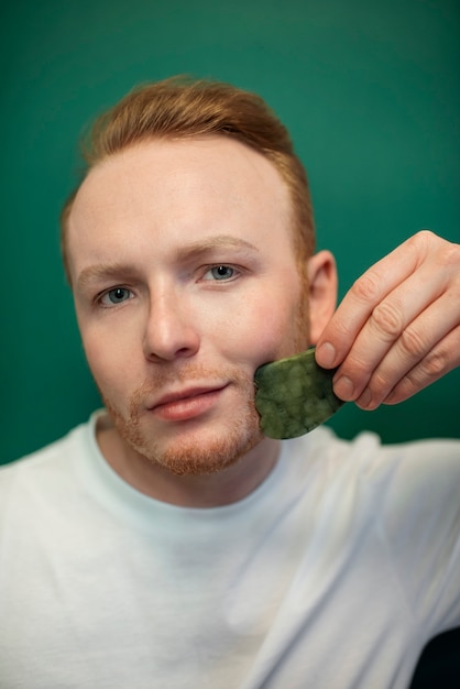 Foto grátis jovem adulto usando produto para cuidados com o rosto