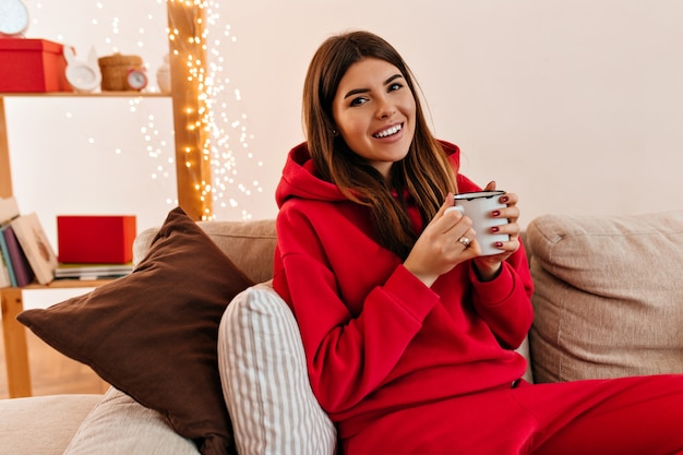 Jovem afável bebendo café da manhã. tiro interno de menina feliz com uma xícara de chá.