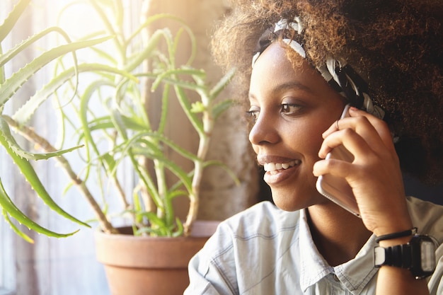 jovem africana com cabelos cacheados falando ao telefone