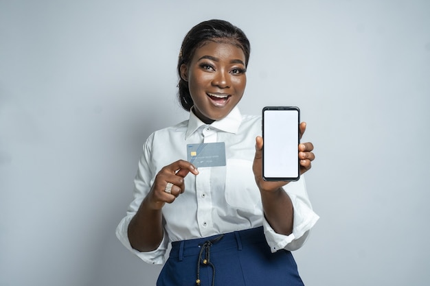 Foto grátis jovem africana recomendando compras online enquanto segura um cartão e um smartphone