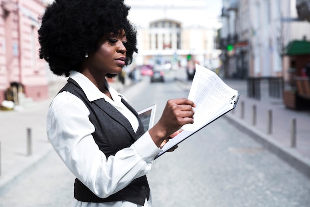 Jovem, africano, mulher negócios fica, ligado, estrada, leitura, a, documento, ligado, área de transferência