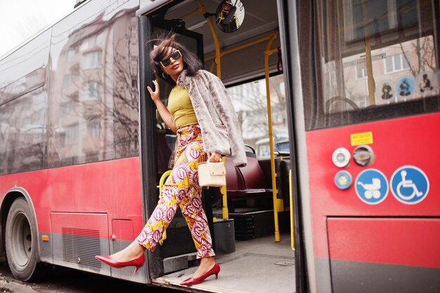 Jovem afro-americana elegante em óculos de sol modernos andando de ônibus