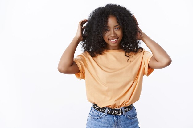 Foto grátis jovem afro-americana sorridente atraente tocando cabelo encaracolado