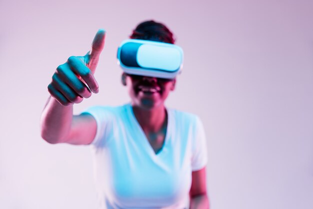 Jovem afro-americana usando óculos VR em luz de néon