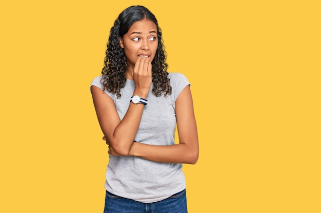 Foto grátis jovem afro-americana vestindo roupas casuais parecendo estressada e nervosa com as mãos na boca roer unhas problema de ansiedade