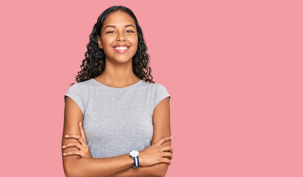 Jovem afro-americana vestindo roupas casuais rosto feliz sorrindo com os braços cruzados olhando para a câmera pessoa positiva