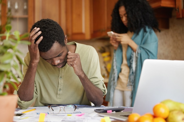 Jovem afro-americano desempregado, enfrentando problemas financeiros, sentindo-se deprimido e frustrado