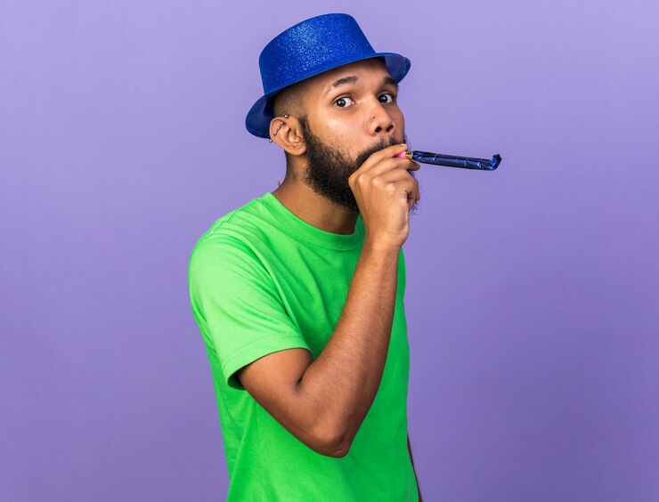 Foto grátis jovem afro-americano satisfeito com chapéu de festa e apito de festa