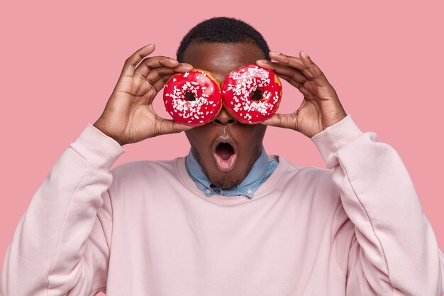 Jovem afro-americano segurando rosquinhas saborosas