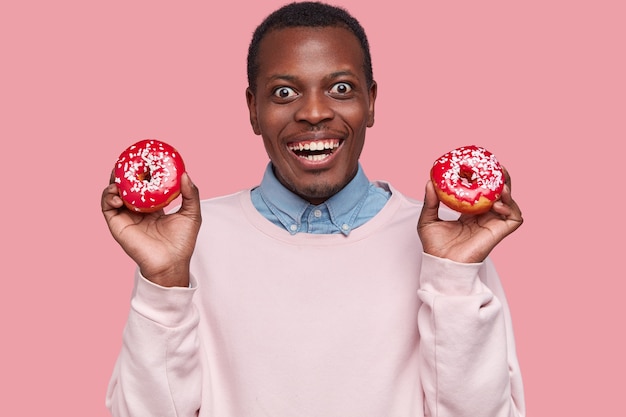 Jovem afro-americano segurando rosquinhas saborosas