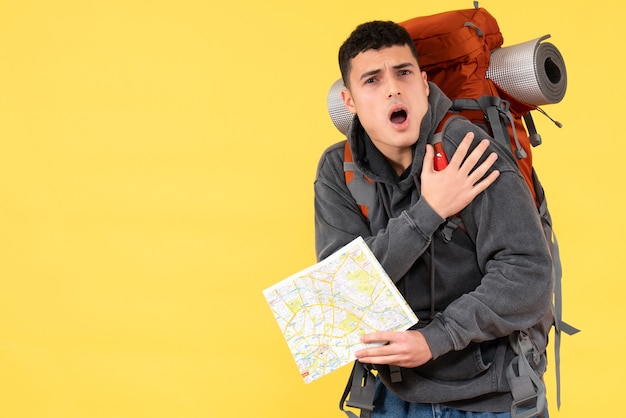 Jovem agitado de frente com uma mochila vermelha segurando um mapa de viagens