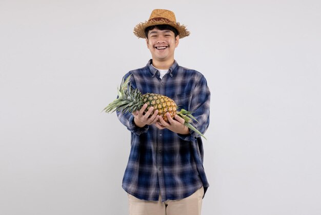 Jovem agricultor asiático mostra frutas orgânicas de abacaxi em fundo branco