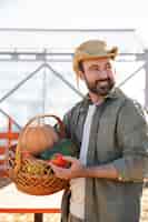 Foto grátis jovem agricultor segurando uma cesta com legumes de sua fazenda
