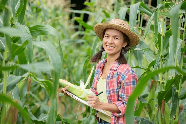 Jovem agricultor sorridente em pé no campo de milho na primavera