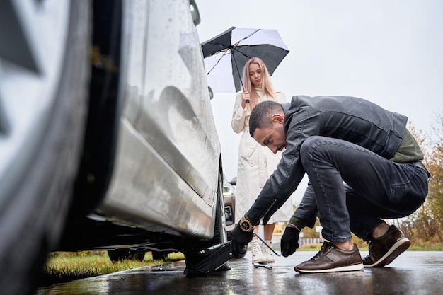 Foto grátis jovem ajudando mulher bonita a consertar carro na estrada