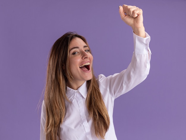 Foto grátis jovem alegre e bonita caucasiana em pé com o punho erguido no roxo