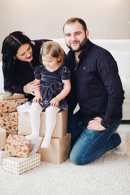 Foto grátis jovem alegre e caucasiana mãe e lindo pai brincando com seu filho perto da árvore de natal