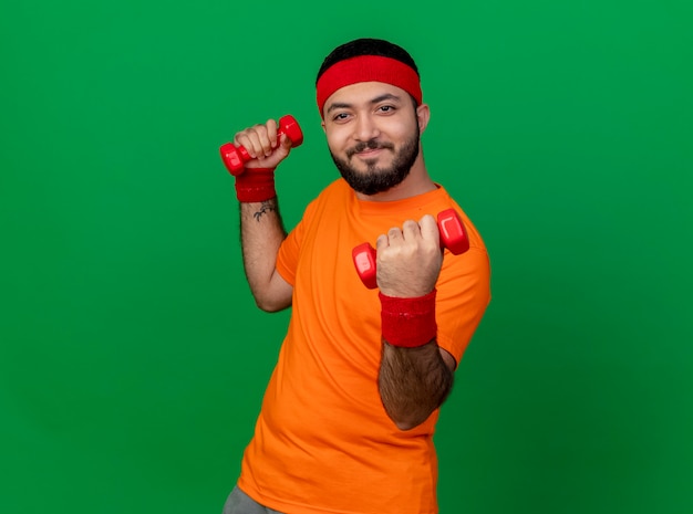 Jovem alegre e esportivo usando bandana e pulseira, fazendo exercícios