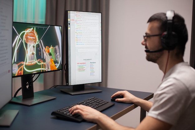 Jovem alegre em seu quarto jogando videogame online no computador.