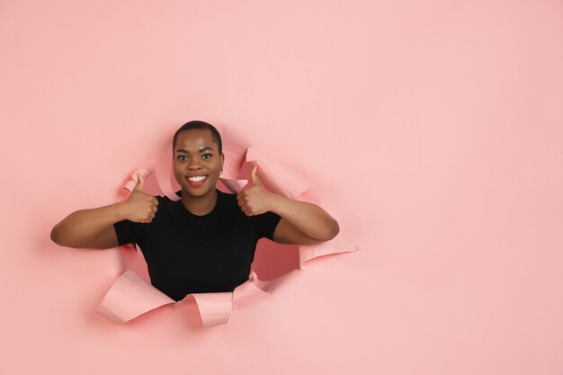 Jovem alegre posa emocionalmente e expressivamente na parede rasgada do buraco do papel coral