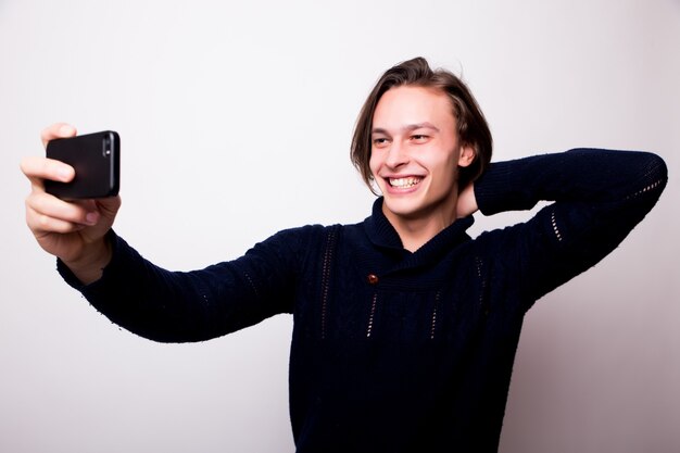 Jovem alegre tirando uma selfie com um smartphone preto