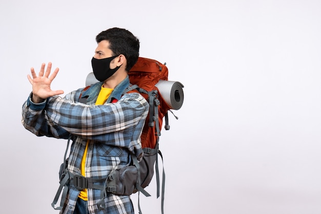 Foto grátis jovem alpinista de frente com mochila e máscara tentando parar algo