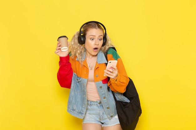 jovem aluna com roupas modernas usando um telefone amarelo