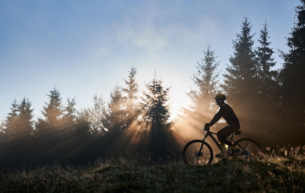 Jovem andando de bicicleta nas montanhas no início da manhã