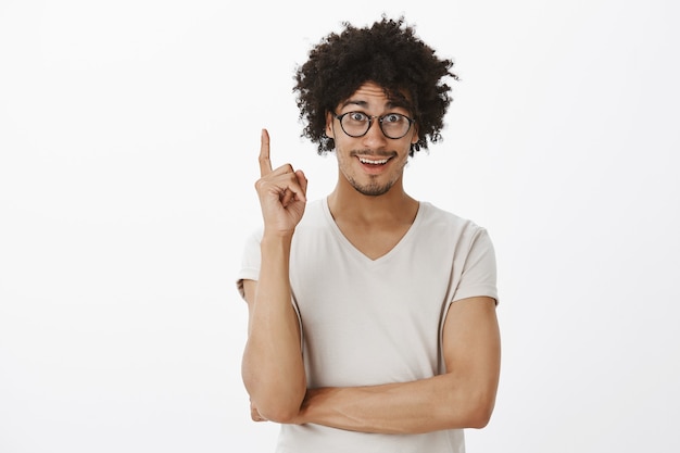 Foto grátis jovem animado, estudante tem uma ideia, levantando dedo e sorrindo feliz