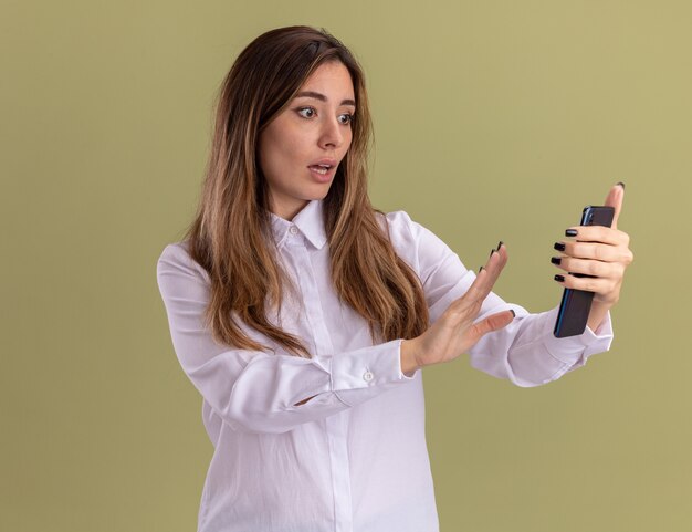 Jovem ansiosa e bonita caucasiana olhando e segurando a mão para o telefone