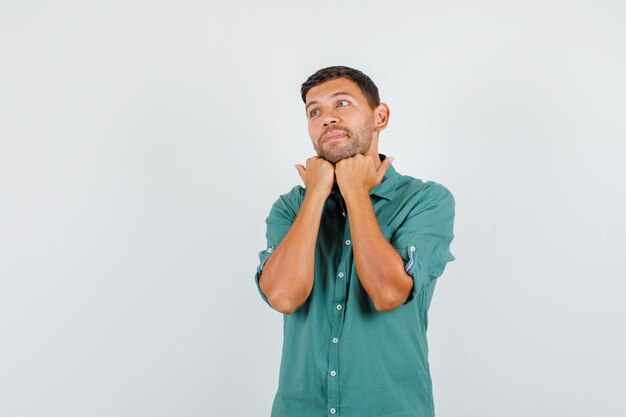 Jovem apoiando o queixo nos punhos da camisa e parecendo um sonhador