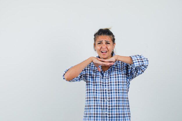 Jovem, apoiando-se nas mãos na camisa quadriculada e parecendo animada.