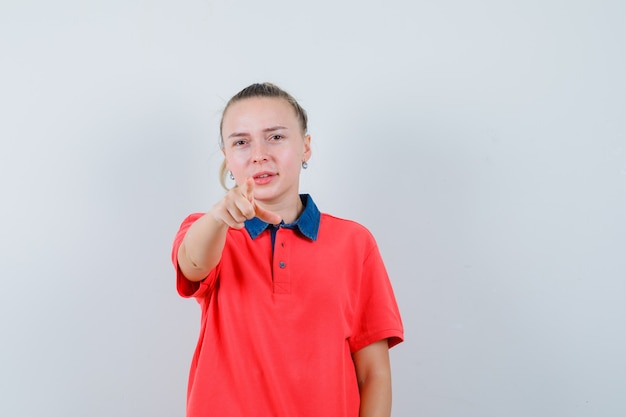 Jovem apontando para a frente com uma camiseta e parecendo confiante