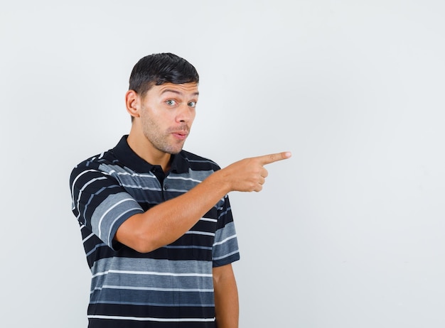 Foto grátis jovem, apontando para longe em t-shirt e parecendo snoopy. vista frontal.