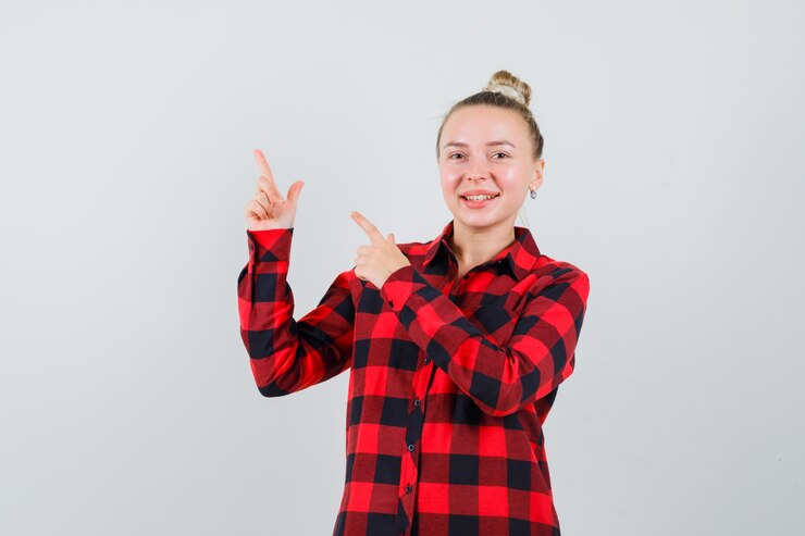 Foto grátis jovem apontando para o canto superior esquerdo com uma camisa xadrez e parecendo feliz