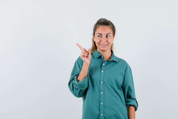 Jovem apontando para o lado com uma camisa azul e parecendo feliz