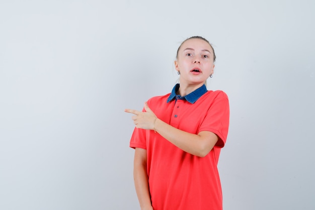 Jovem apontando para o lado em uma camiseta e parecendo ansiosa