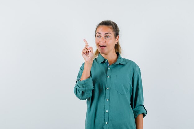 Jovem apontando para trás com uma camisa azul e parecendo curiosa